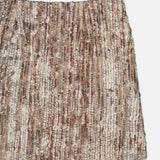 A close-up of the BRUNELLO CUCINELLI Wool Diamante Boucle Tweed Mini Skirt, crafted in Italy, showcases a woven blend of cream, beige, and brown tones with shimmering metallic accents. The boucle tweed fabric features intricate sequin embroidery for added detail.