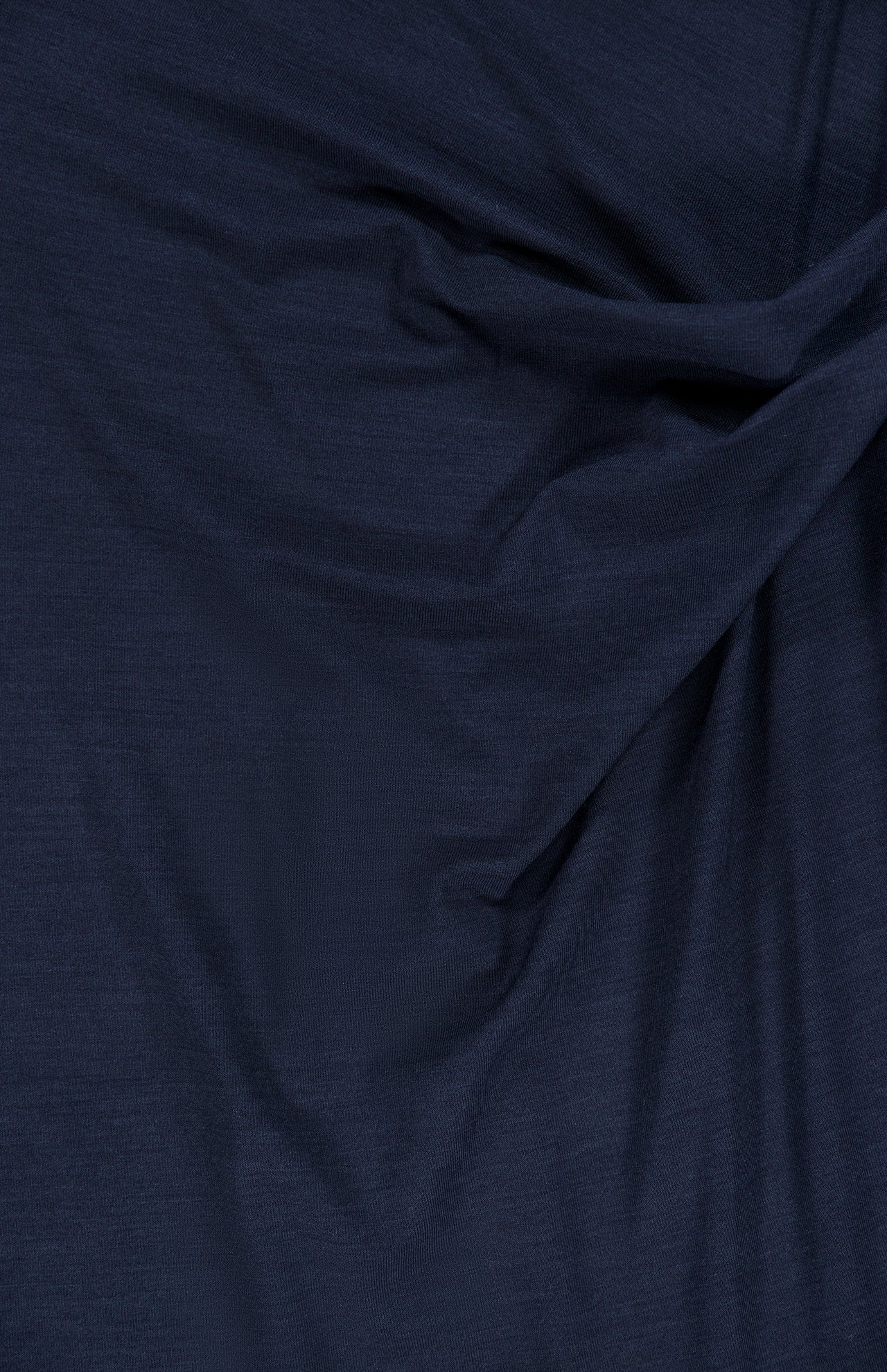 Luxurious dark navy wool jersey by BRUNELLO CUCINELLI features a gentle drape and subtle sheen, with softly textured wrinkles that highlight the play of light and shadow—an ideal fabric for the sophisticated Wool Jersey Wrap Dress.