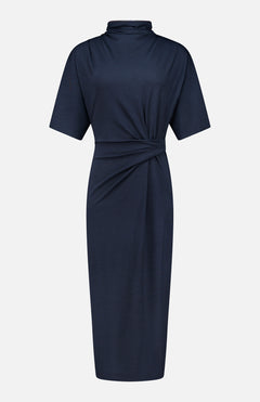 BRUNELLO CUCINELLI’s Wool Jersey Wrap Dress in navy features a knee-length silhouette with short sleeves, a high neckline, and a gathered twist detail at the waist. Simple yet refined, this elegant dress is displayed against a plain white background.