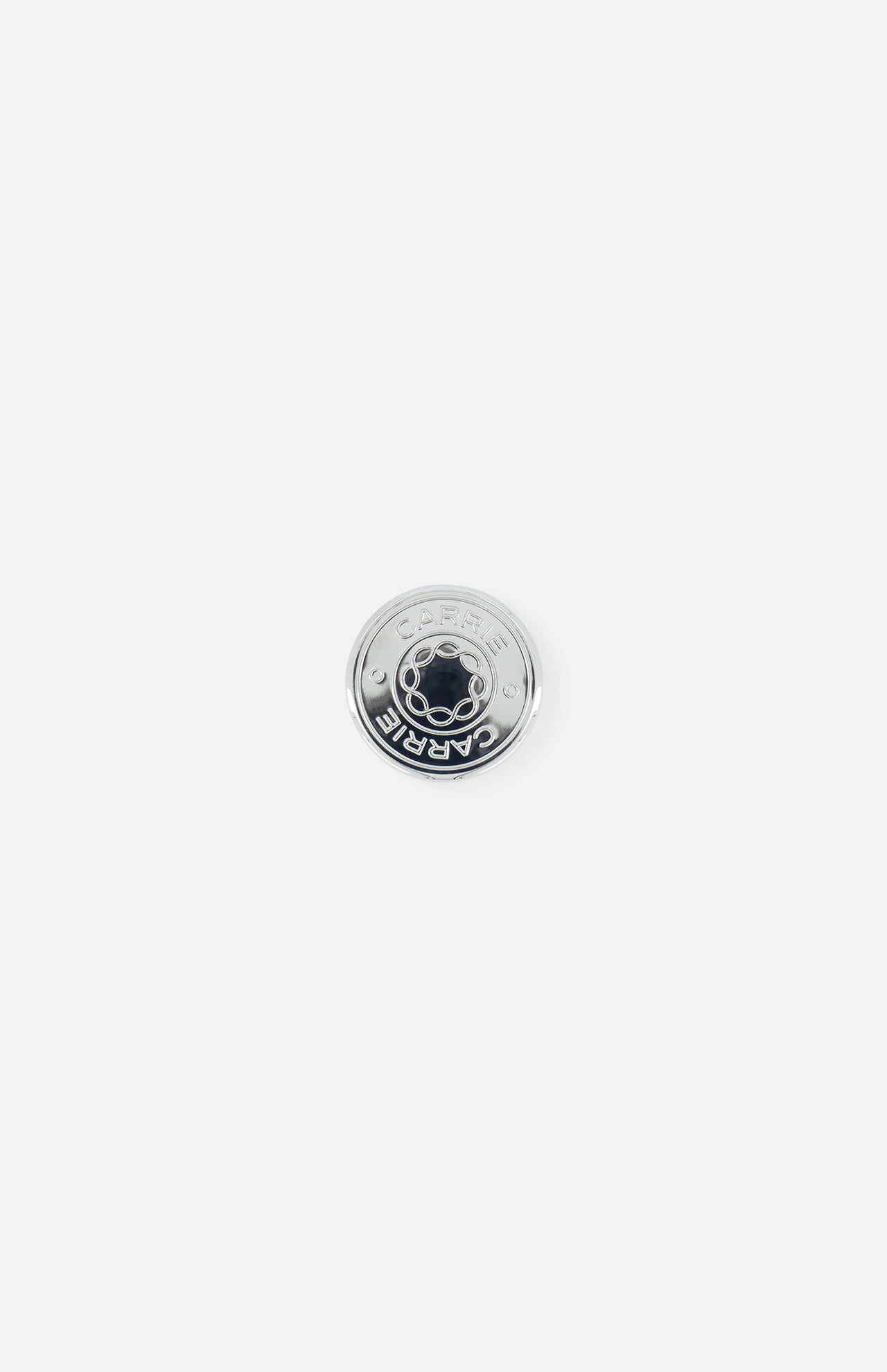 A round Nespresso capsule with a silver top and "CAFÉ" written on it is placed next to the Carrie Purse Hook in Silver by CARRIE ATELIER, shown on a plain white background.