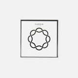 A square white box with a black border and abstract circular motif indicates the stylish anti-slip Carrie Purse Hook in Yellow Gold inside. CARRIE ATELIER is printed above in black on the clean white background.