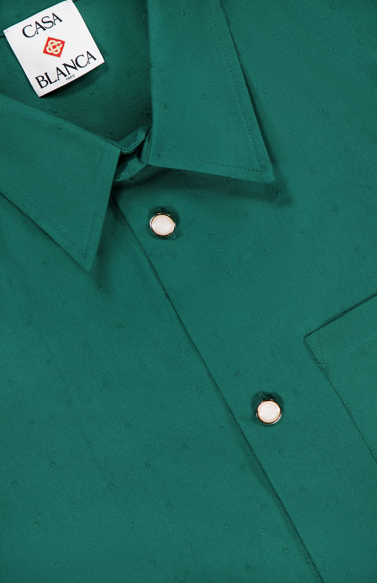 Close-up of the green CASABLANCA Piquet Logo Long Sleeve Shirt featuring a pointed collar, silver and white buttons, chest pocket, and visible Casa Blanca label inside the collar.