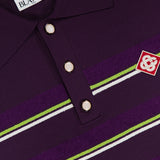 Close-up of the CASABLANCA Stripe Short Sleeve Polo Shirt in dark purple, showcasing green and white stripes, three metallic buttons, and an embroidered red and white logo patch on the chest.