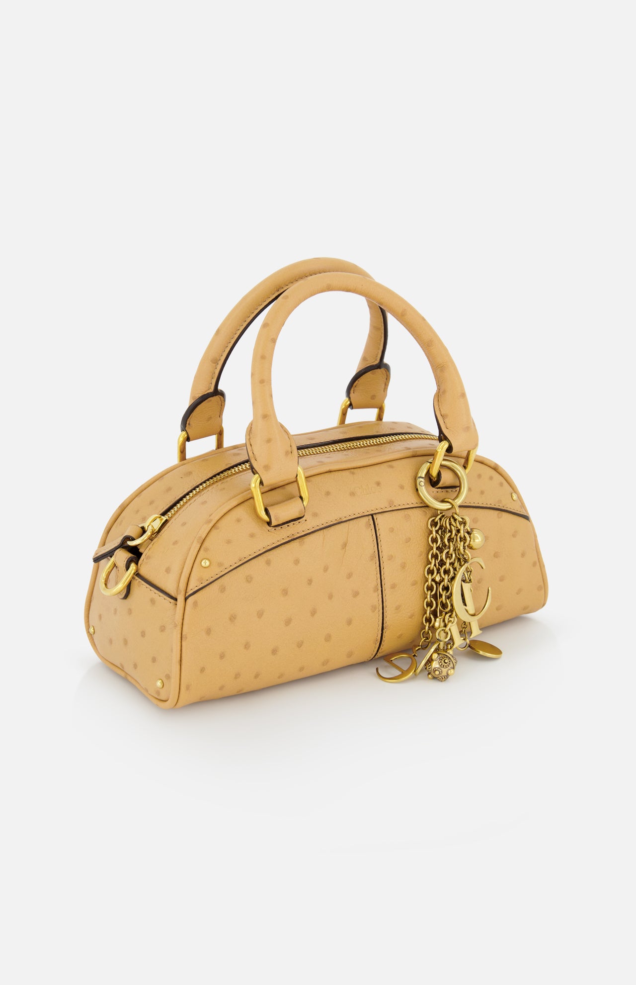 The CHLOÉ Ostrich-effect Bowling Hand Bag is a small, light tan bag with gold hardware, two handles, a zipper closure, and gold chain charms on one handle, shown against a white background.