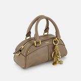 The CHLOÉ Bowling Hand Bag with Charms features taupe leather, gold hardware, dual handles, a zip closure, and decorative gold charms on one handle, shown against a plain white background.
