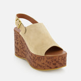The Maxime Carved Wedge Heel by CHLOÉ is a tan suede platform sandal with an open toe, slingback strap, wood-effect wedge heel, graffiti-style thick brown sole, gold buckle, and is made in Italy.