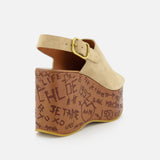The CHLOÉ Maxime Carved Wedge Heel is a tan suede platform sandal with a buckle strap, thick brown sole, hand-drawn black graffiti-style details, and "CHLOE" text. Crafted from premium materials in Italy.