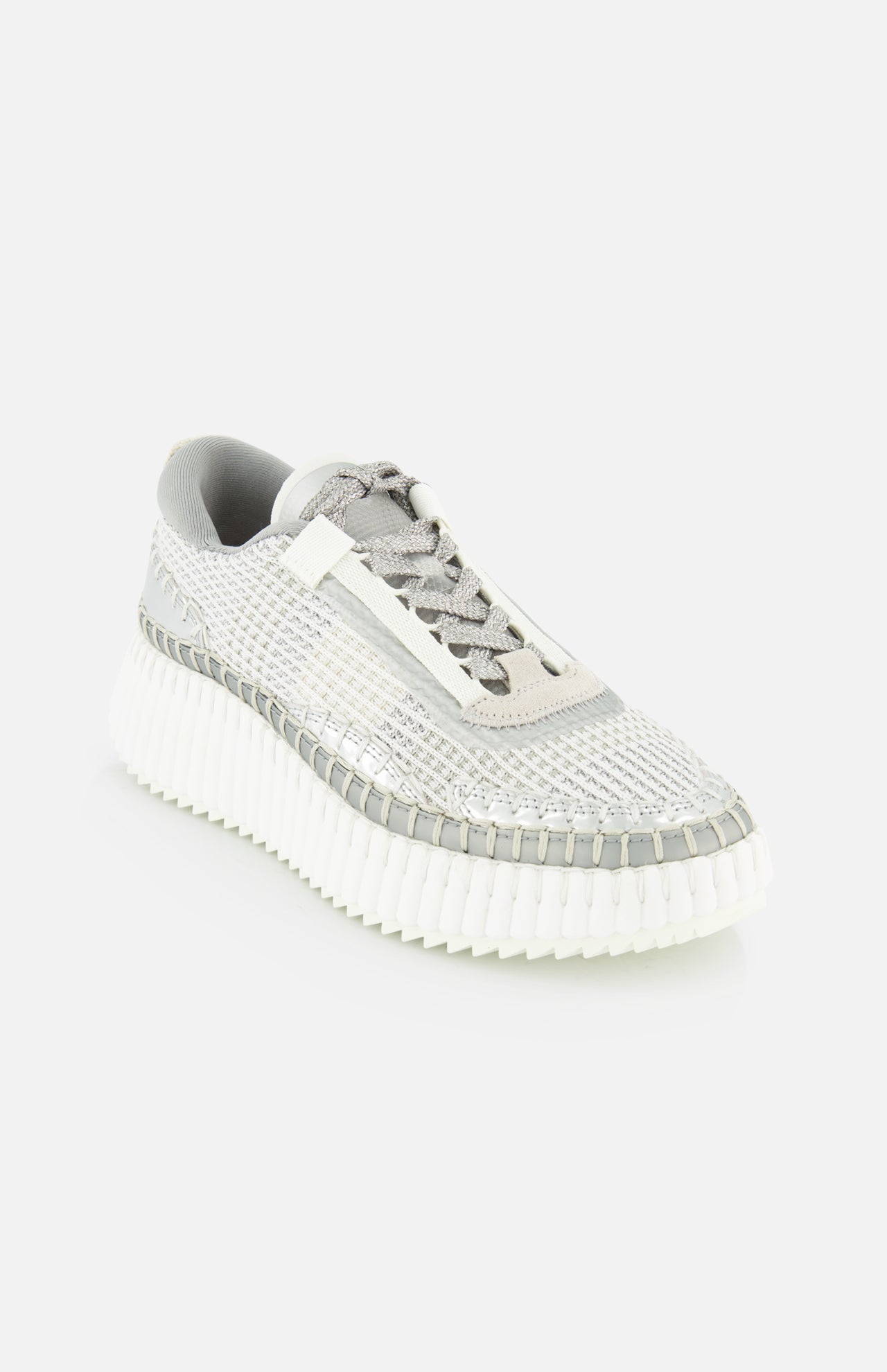 The CHLOÉ Metallized Nama Sneakers feature a textured gray and white woven upper, metallic details, and a chunky ridged recycled sole, shown angled on a light background for a modern luxe athleisure look.