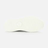 The image shows the bottom view of CHLOÉ Metallized Nama Sneakers' white sole with a ridged, grooved texture and a circular logo at the center, highlighting its recycled sole against a plain white background.