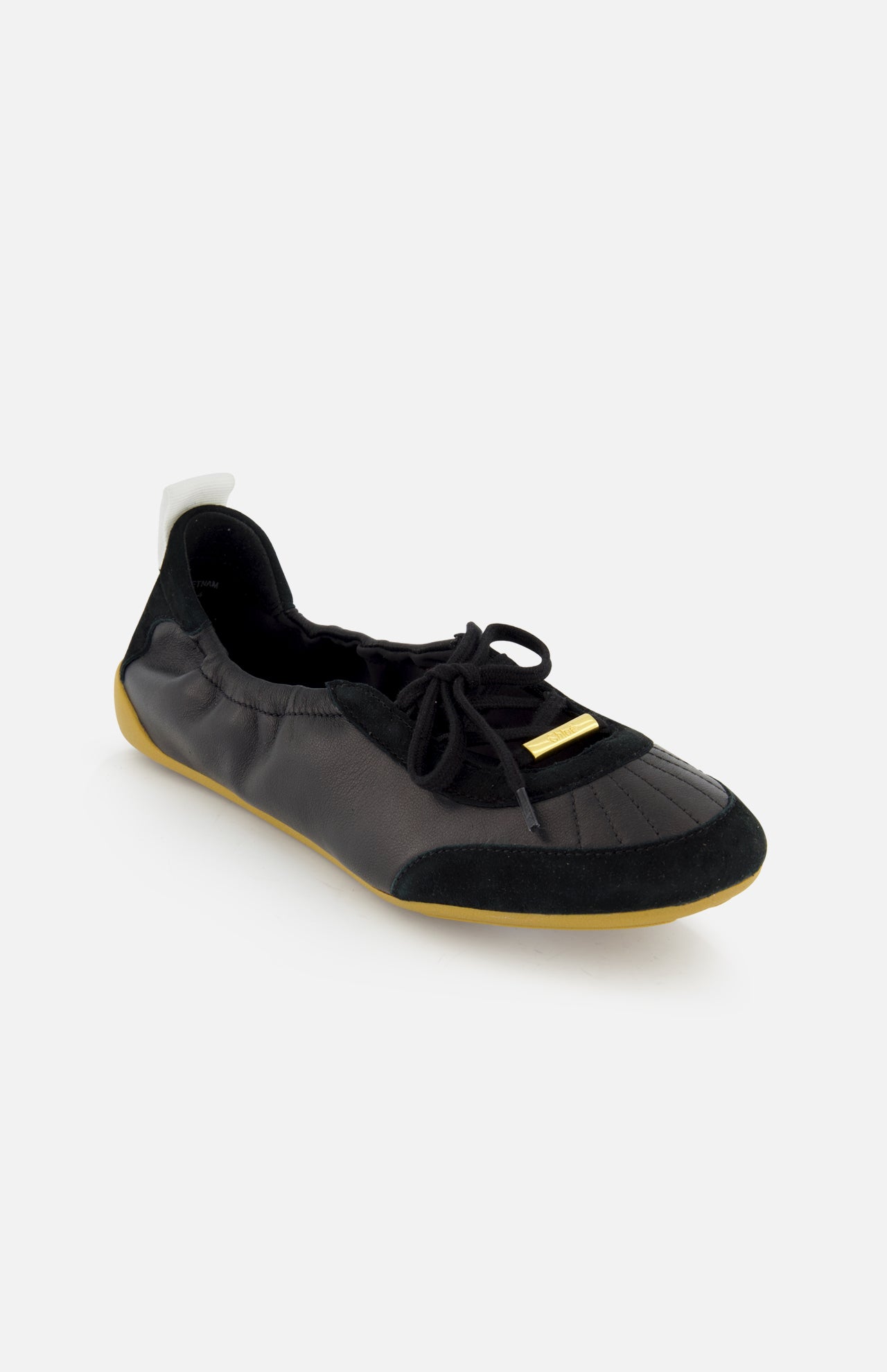 The CHLOÉ Laced Kick Flats are sporty black ballet shoes with laces, a suede toe cap, gold accents, a white heel pull tab, and a light brown rubber sole—an elegant addition to your flat collection.
