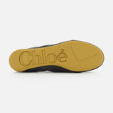 The image shows the yellow rubber sole of the CHLOÉ Laced Kick Flats, with "CHLOÉ" embossed in large letters. The rest of this black sporty ballet flat is only partially visible.