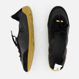 Two CHLOÉ Laced Kick Flats in black with tan rubber soles are displayed on a white background—one upright, showing the sporty ballet shoe style, and the other from above for a clear view of these stylish flats by Chloé.
