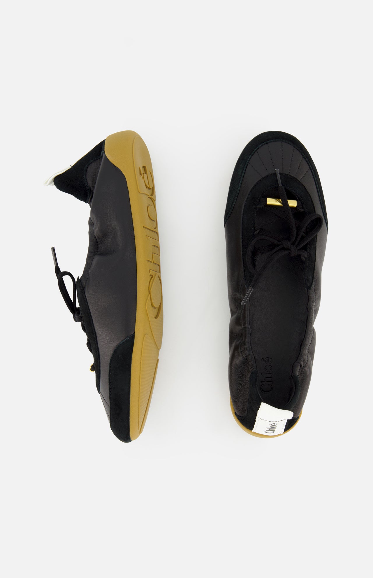 Two CHLOÉ Laced Kick Flats in black with tan rubber soles are displayed on a white background—one upright, showing the sporty ballet shoe style, and the other from above for a clear view of these stylish flats by Chloé.