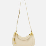 The CHLOÉ Slim Banana Bag is a cream-toned, crescent-shaped handbag with gold hardware, a long adjustable strap, and leather top handle. Made in Italy, it features a small gold keychain and lock detail on one side.