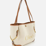The CHLOÉ Cotton Clover Bag is a beige cotton tote featuring brown leather handles and trim, accented with gold chains and prominently displaying the CHLOÉ logo on the front. Ideal as a stylish office accessory, this designer bag is showcased against a plain white background.