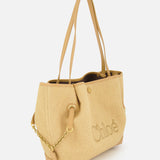 The CHLOÉ Raffia Clover Bag is a beige woven raffia tote featuring tan leather trim handles, gold-tone chain detailing, and “Chloé” embroidered on the side, shown against a plain white background.