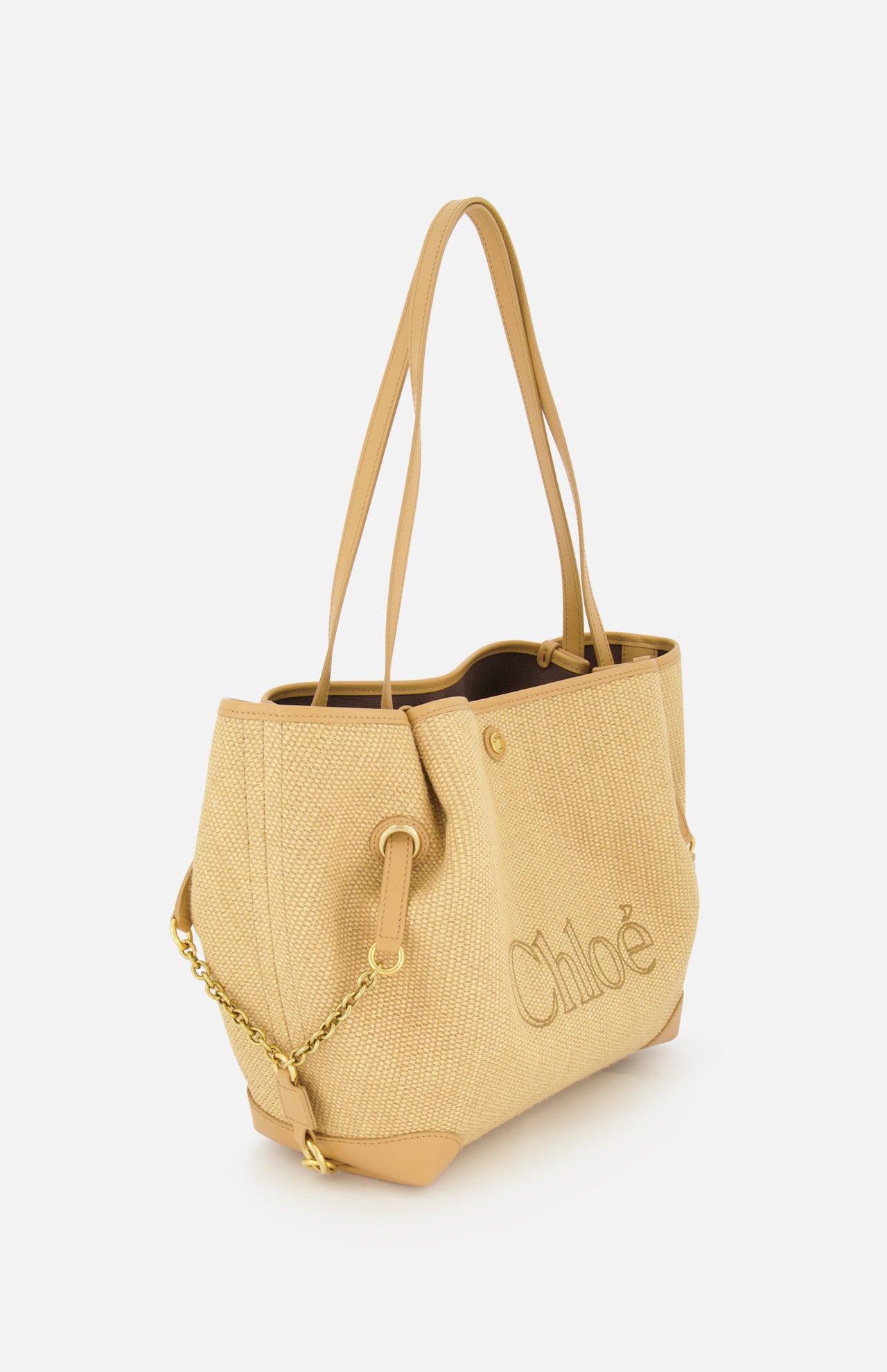 The CHLOÉ Raffia Clover Bag is a beige woven raffia tote featuring tan leather trim handles, gold-tone chain detailing, and “Chloé” embroidered on the side, shown against a plain white background.