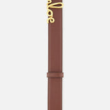The Chloé Iconic Belt by CHLOÉ is crafted from rich brown leather and features a gold buckle elegantly shaped to spell out “Chloé” in cursive script, showcased against a white background.
