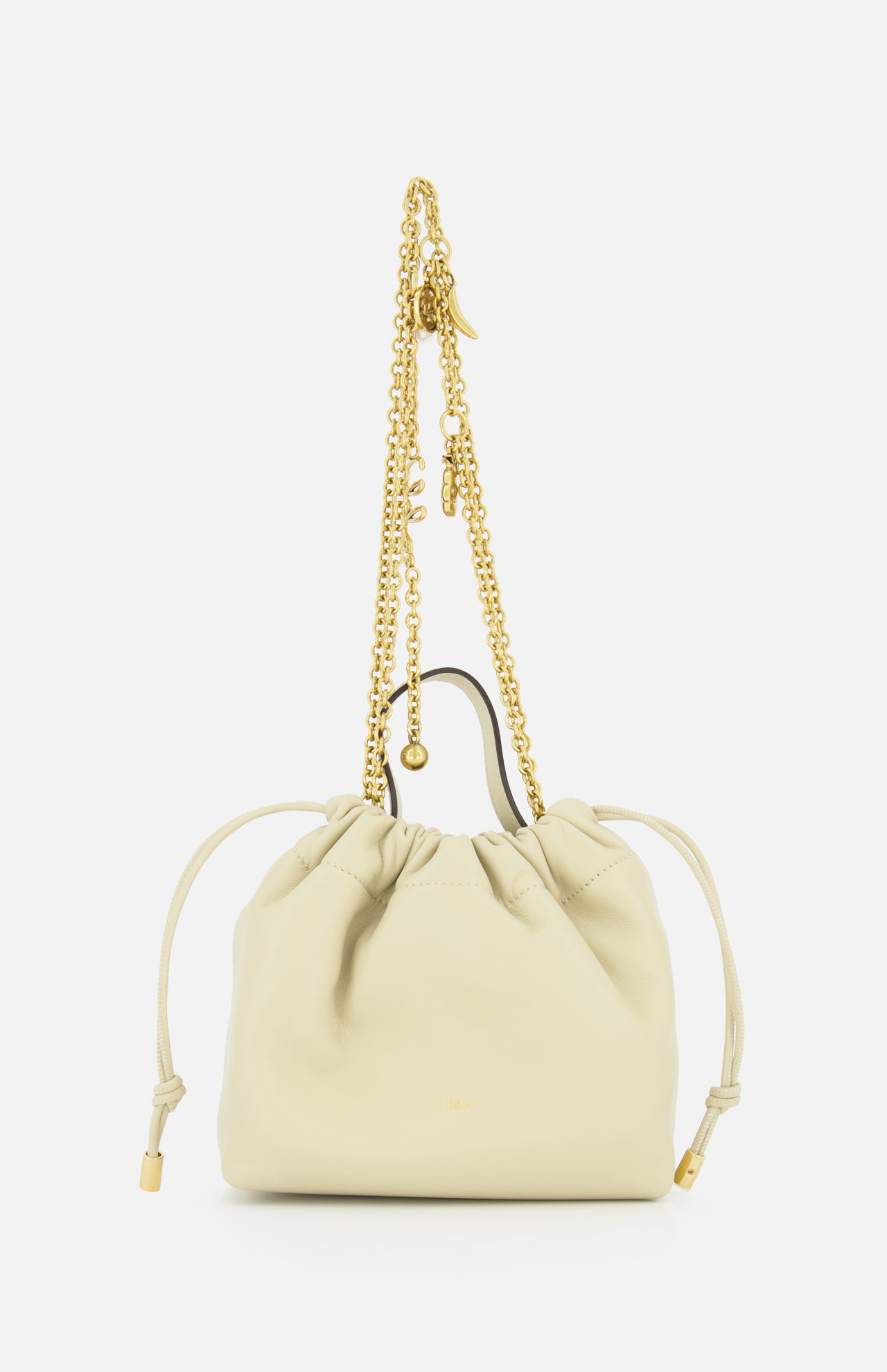 The CHLOÉ Chloé Icons Chain Strap Bag is a small cream leather handbag featuring slim side ties and a decorative gold chain handle embellished with charms, shown against a white background. This elegant mini shoulder bag exudes refined simplicity, echoing the timeless, effortless style characteristic of CHLOÉ.