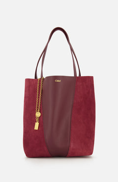 A CHLOÉ Leather and Suede Spin Bag in burgundy, featuring leather and suede panels, gold chain and padlock charm, double handles, and a removable bag chain for added versatility. Displayed against a plain white background.