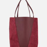 The CHLOÉ Leather and Suede Spin Bag showcases a modern minimalist design with a burgundy leather center panel, suede side panels, two handles, and a removable bag chain for versatile carrying options.