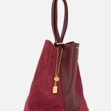 The CHLOÉ Leather and Suede Spin Bag combines burgundy suede and leather with elegant gold chain accents and a lock charm. Featuring a looped leather handle, this sophisticated tote also includes a removable bag chain for versatile styling options.