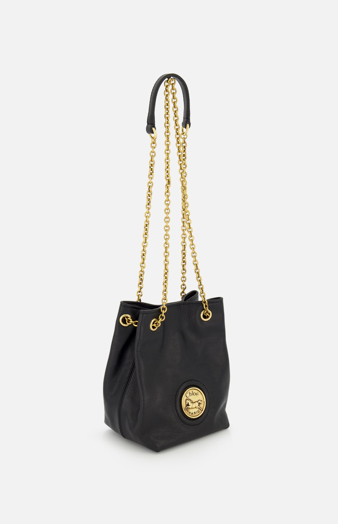 The CHLOÉ Mini Horse Medal Leather Bag is a black leather bucket bag with gold chain crossbody strap, gold hardware, and a circular gold emblem with embossed branding. The mini bag stands upright on a plain white background.