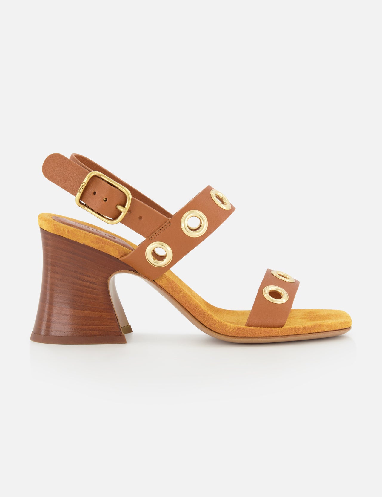 The Janis Slingback Grommet Heels by CHLOÉ feature brown leather with gold buckle and grommet accents, a yellow insole, and a flared wooden block heel, displayed in profile against a white background.