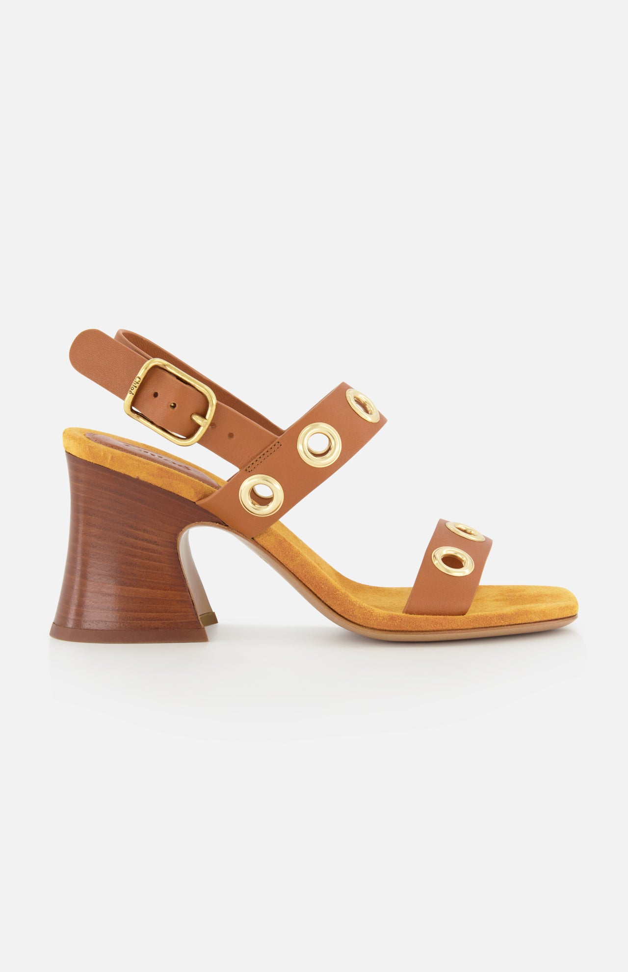 The Janis Slingback Grommet Heels by CHLOÉ feature brown leather with gold buckle and grommet accents, a yellow insole, and a flared wooden block heel, displayed in profile against a white background.