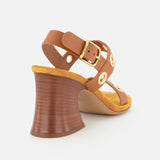 The Janis Slingback Grommet Heels by CHLOÉ—a pair of ginger brown leather slingback sandals with gold buckle and rounded gold grommet accents, featuring a flared wooden block heel and a tan insole—are shown from the back left side against a white background.