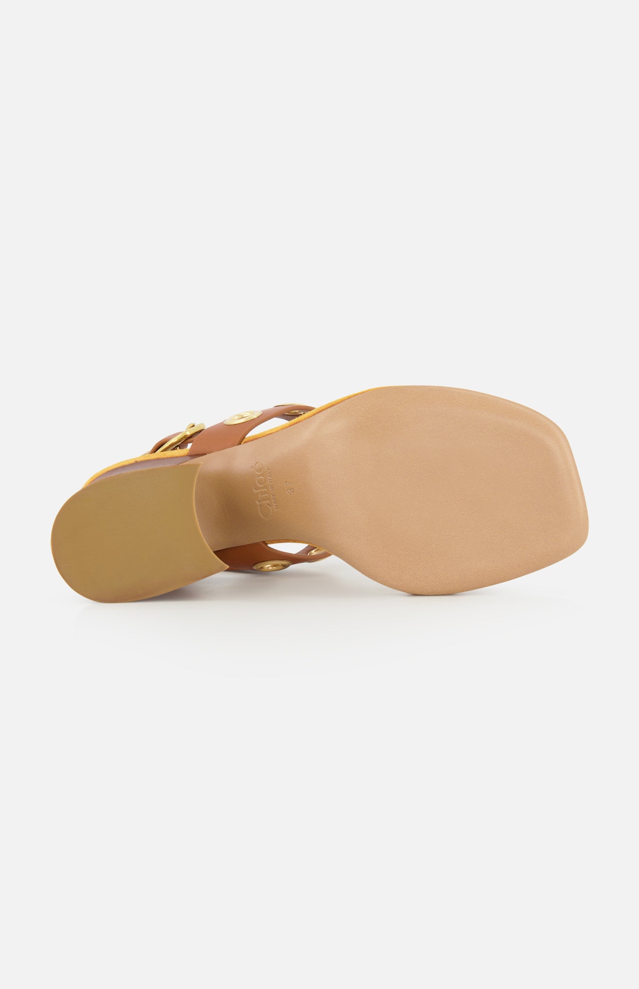 A close-up view of the sole of the CHLOÉ Janis Slingback Grommet Heels, highlighting its ginger brown leather, square toe design, and smooth light brown bottom against a white background.