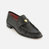 The Letti Gold Heart Loafers by CHLOÉ feature black leather construction with a gold heart-shaped embellishment on the strap, a low heel, and striking red interior lining. Displayed against a white background, these flats blend classic style with playful elegance, making them the perfect feminine choice for any occasion.