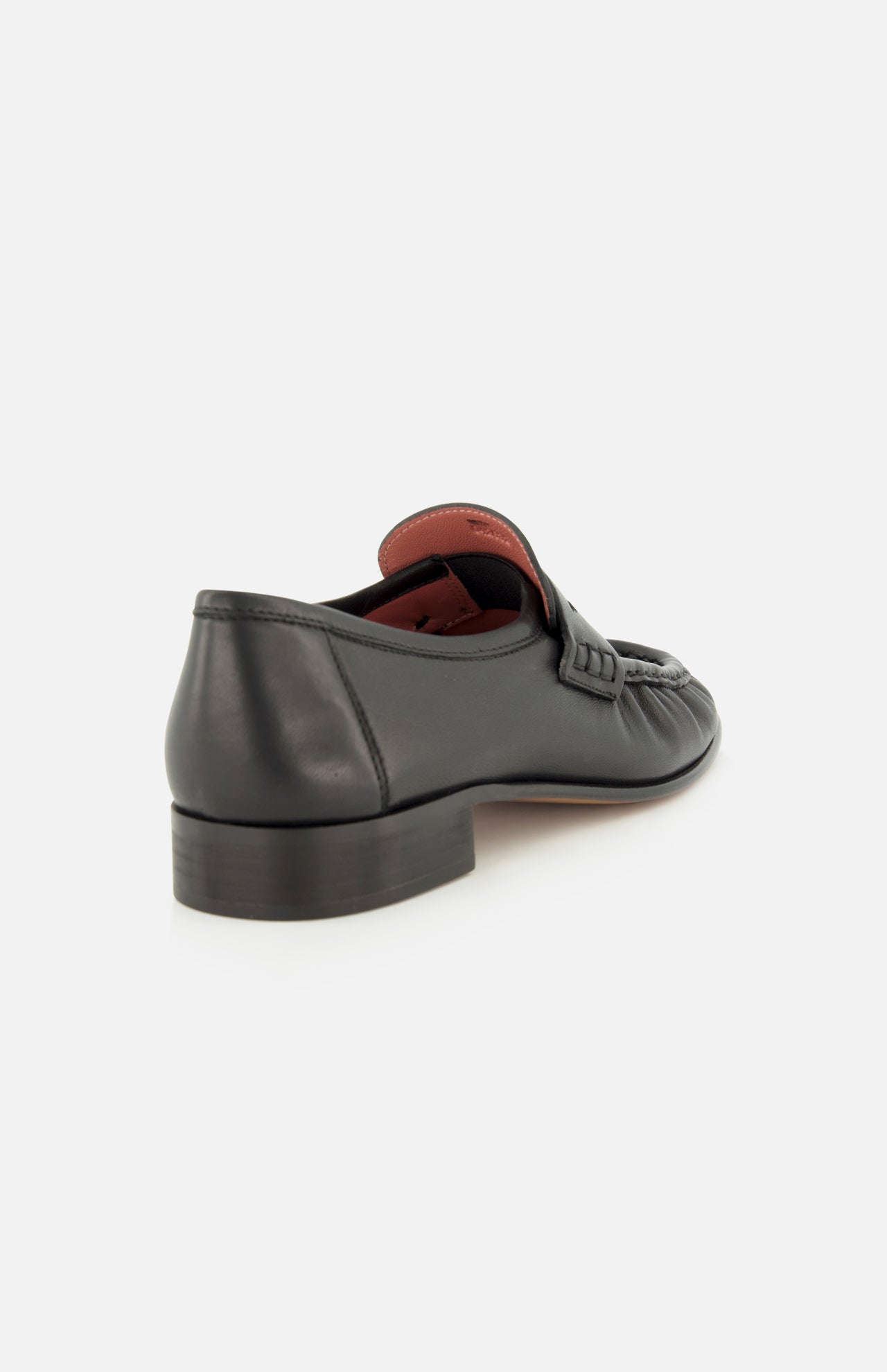 The CHLOÉ Letti Gold Heart Loafers feature black leather in a classic loafer silhouette, with a low heel. Viewed from the back and side, the shoe reveals a dark brown sole and a glimpse of its signature red interior lining.