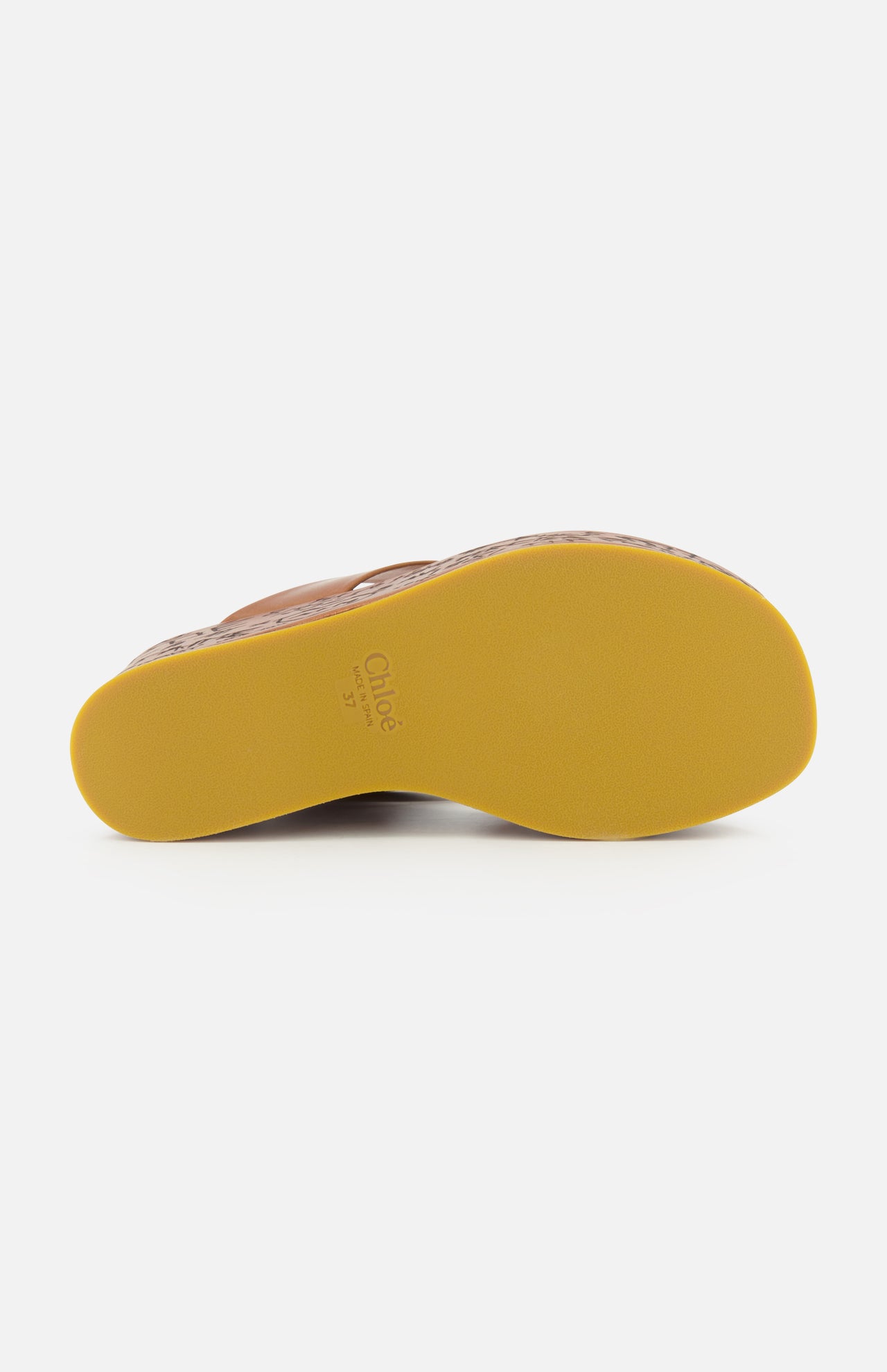 The image displays the yellow rubber sole of a brown CHLOÉ Maxime Wedged Thong Sandal, viewed from the bottom on a white background. The brand name and size—CHLOÉ 37—are visible near the heel. This stylish design features a wood-effect platform, enhancing the modern aesthetic of these wedge sandals.