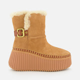 CHLOÉ Nama Suede and Shearling Boots feature tan suede, shearling lining, a gold buckle strap, thick ridged rubber soles, and detailed stitching for a cozy winter style.