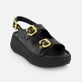 The Nama Buckle Wedge Sandals by CHLOÉ feature black leather, a thick ridged platform sole, two gold buckle straps across the top, and an adjustable gold buckle strap at the heel, shown against a white background.