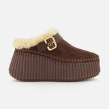 Introducing the Nama Suede Slippers by CHLOÉ—these brown suede platform mules feature a chunky, ridged rubber sole, plush cream shearling lining, and an elegant gold buckle detail at the side. Designed for both comfort and effortless style, these slip-ons are the perfect cozy addition to your wardrobe.