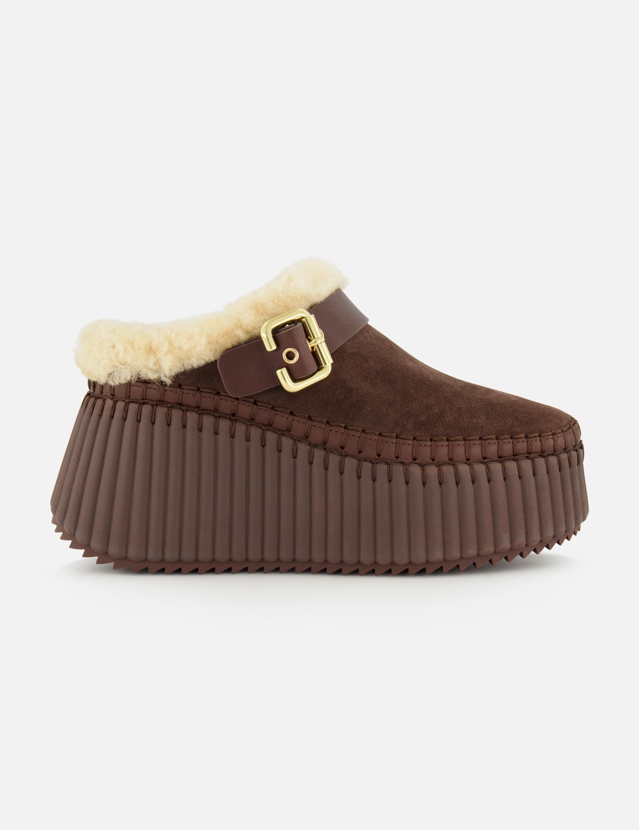 Introducing the Nama Suede Slippers by CHLOÉ—these brown suede platform mules feature a chunky, ridged rubber sole, plush cream shearling lining, and an elegant gold buckle detail at the side. Designed for both comfort and effortless style, these slip-ons are the perfect cozy addition to your wardrobe.