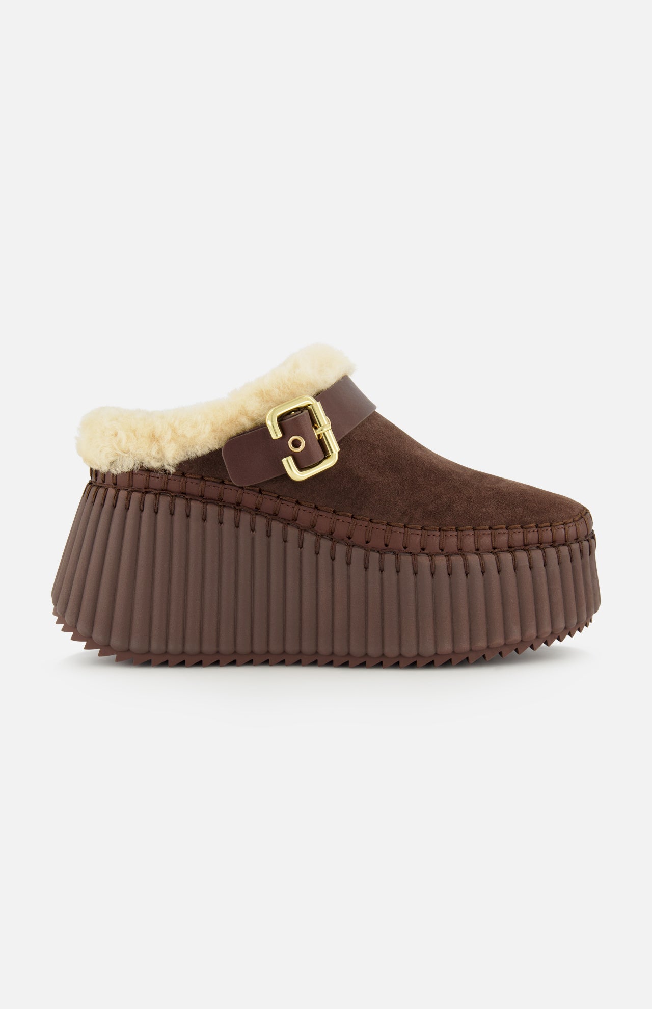 Introducing the Nama Suede Slippers by CHLOÉ—these brown suede platform mules feature a chunky, ridged rubber sole, plush cream shearling lining, and an elegant gold buckle detail at the side. Designed for both comfort and effortless style, these slip-ons are the perfect cozy addition to your wardrobe.