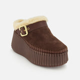 The Nama Suede Slippers by CHLOÉ are brown suede mule platform slip-on clogs featuring a cozy shearling lining, gold buckle detail, and a thick, ribbed brown sole, displayed against a plain white background.
