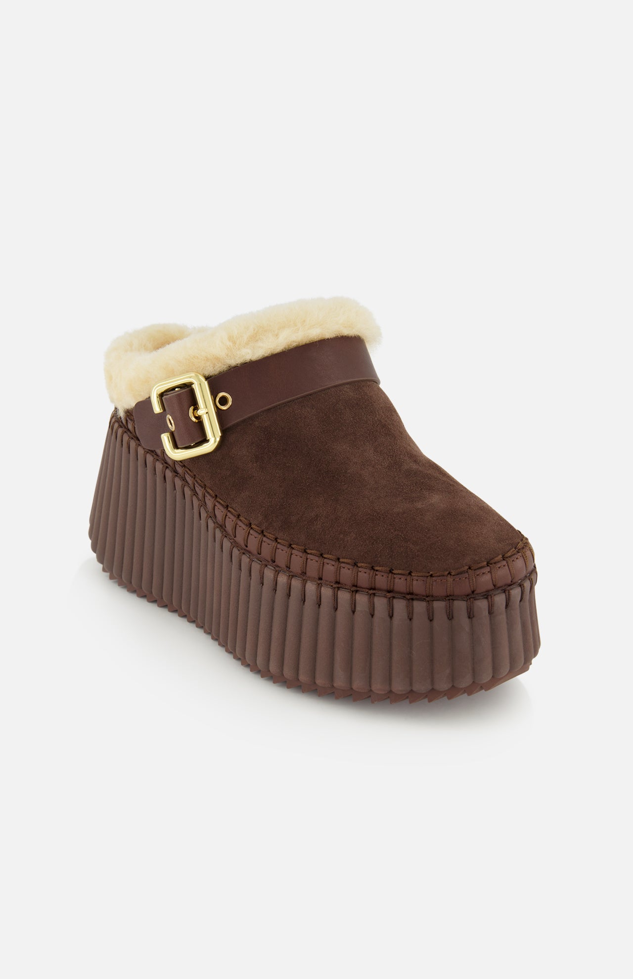 The Nama Suede Slippers by CHLOÉ are brown suede mule platform slip-on clogs featuring a cozy shearling lining, gold buckle detail, and a thick, ribbed brown sole, displayed against a plain white background.