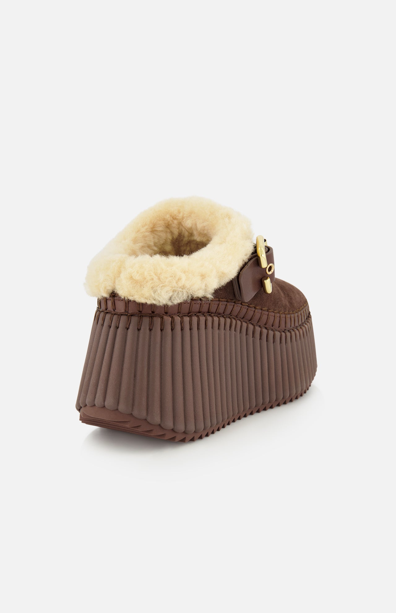 The Nama Suede Slippers by CHLOÉ feature brown suede uppers, a thick ribbed wedge sole, plush cream shearling lining, and a gold buckle detail. Photographed against a plain white background, these chic platform slip-ons effortlessly combine style and comfort.