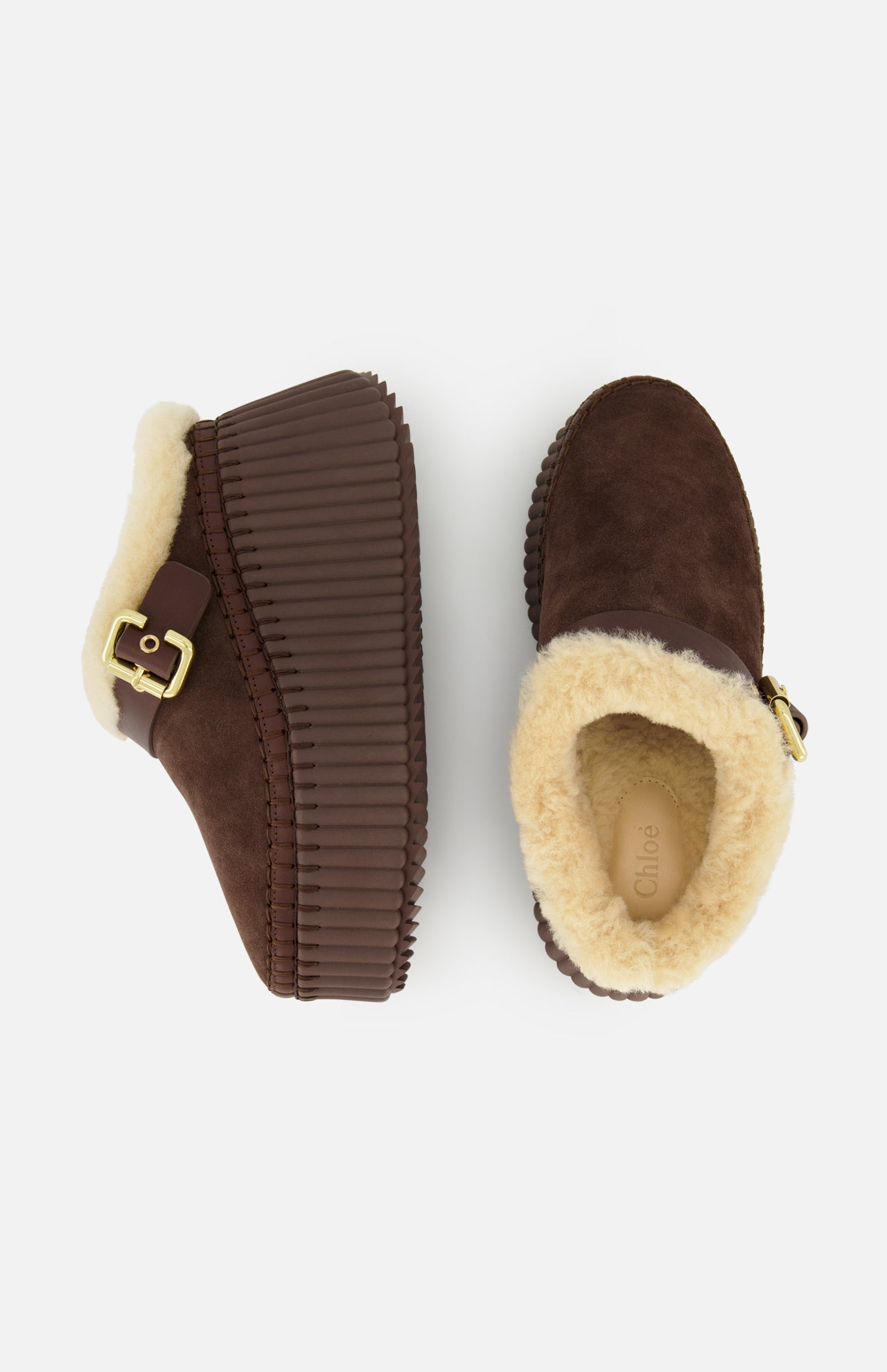 A pair of Nama Suede Slippers by CHLOÉ featuring brown suede mule platform slip-ons with thick, ridged soles, plush shearling lining, and gold buckles. One slipper is displayed from the side and the other from above against a white background.