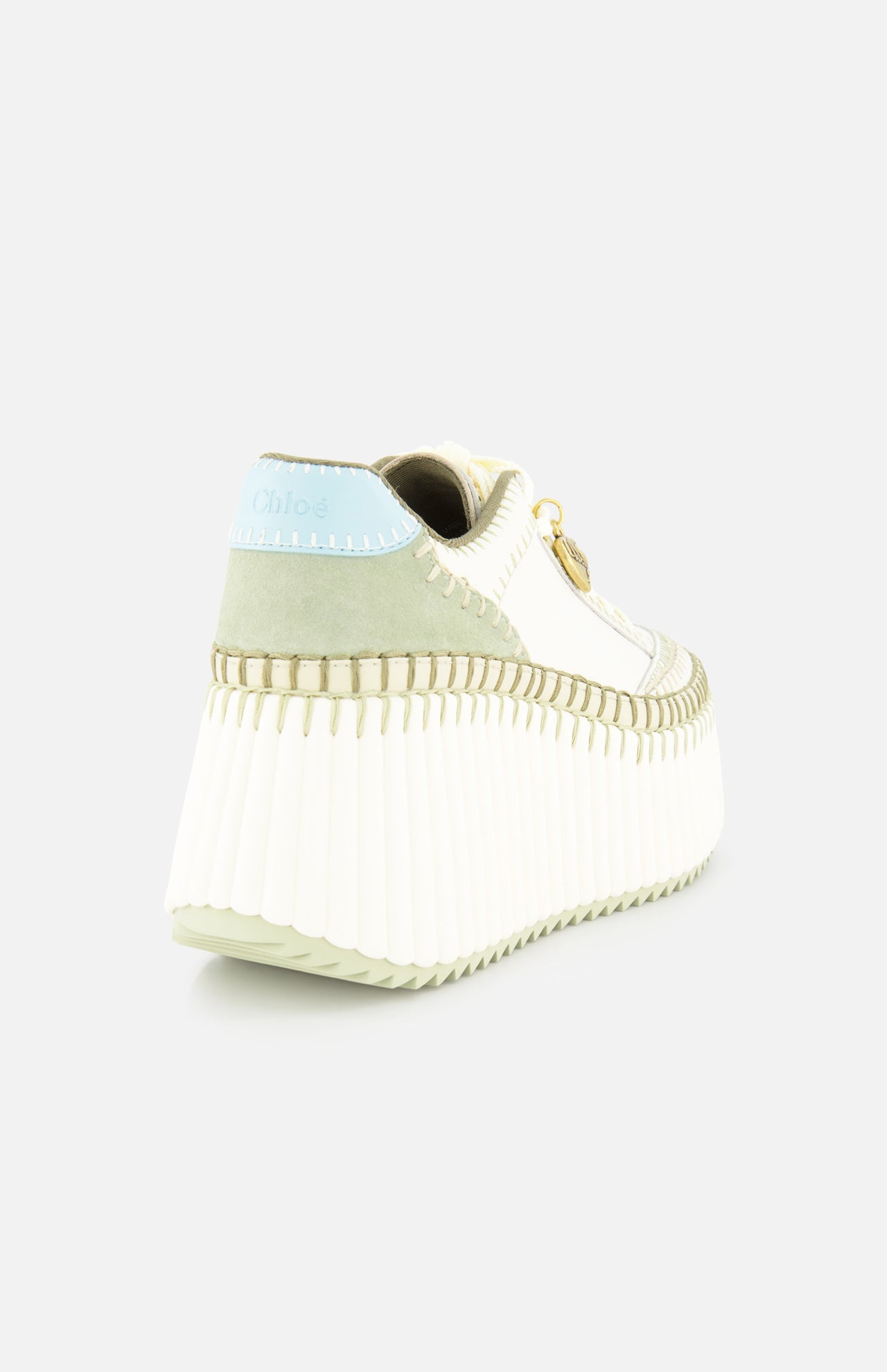 The Nama Charm Detail Sneaker by CHLOÉ features white leather, a recycled wedge sole, ribbed chunky design, pale green and blue suede accents, a gold logo charm, and detailed stitching—shown from the back-left against a white background.