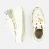 Two CHLOÉ Nama Charm Detail Sneakers with thick recycled soles: one side view reveals a blue-green heel accent, while the top view displays a smiley face and crescent moon charm on the toe.