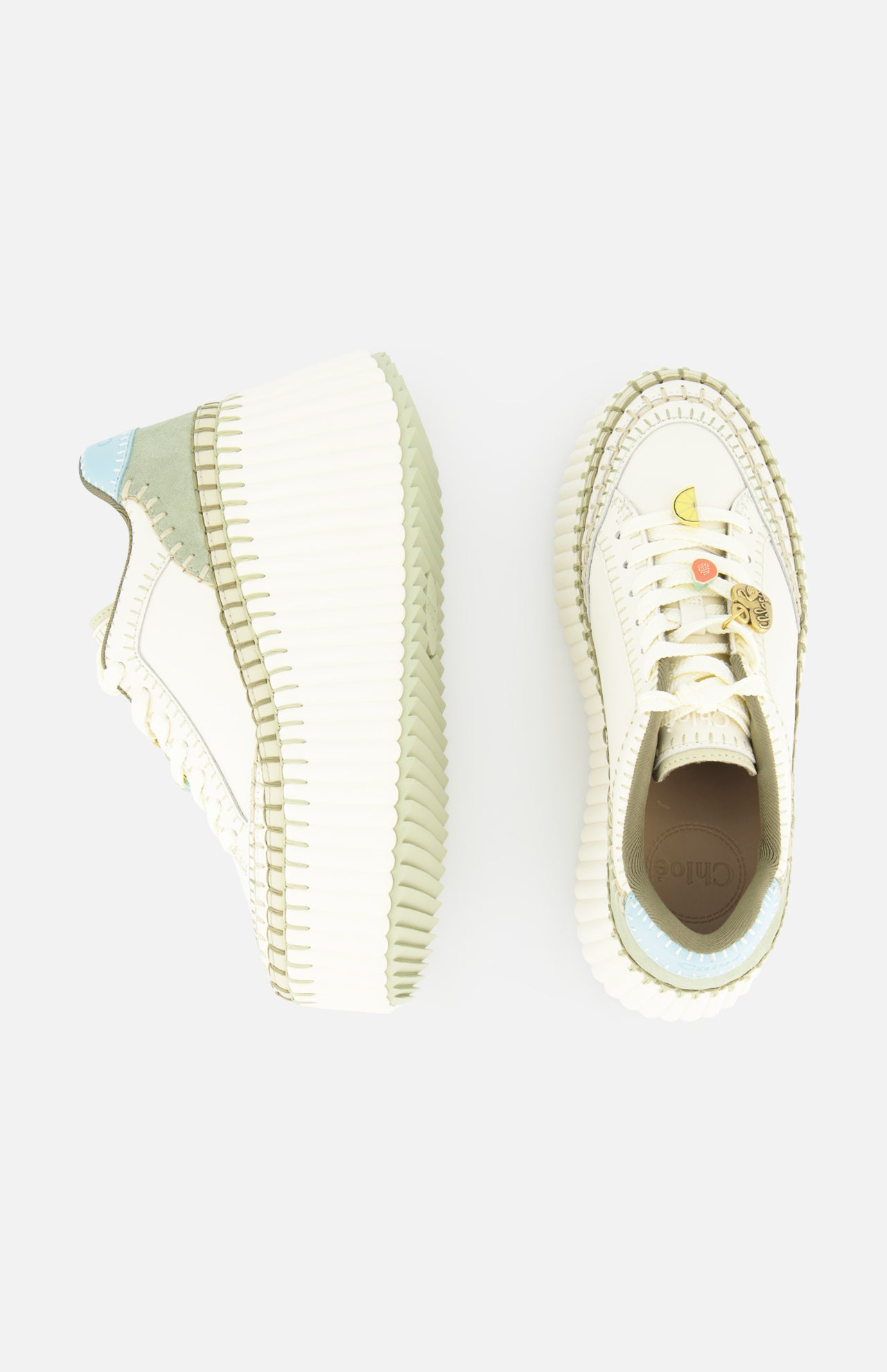 Two CHLOÉ Nama Charm Detail Sneakers with thick recycled soles: one side view reveals a blue-green heel accent, while the top view displays a smiley face and crescent moon charm on the toe.