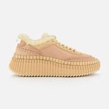 The Nama Shearling Lining Sneakers by CHLOÉ feature a light pink upper with subtle tan stitching, a thick, ridged recycled sole in tan, and a plush cream shearling lining. Presented in profile against a plain white background.