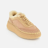 The CHLOÉ Nama Shearling Lining Sneakers feature a beige design with a thick, textured recycled sole, visible stitching, and a plush shearling lining on the inside, displayed on a white background.