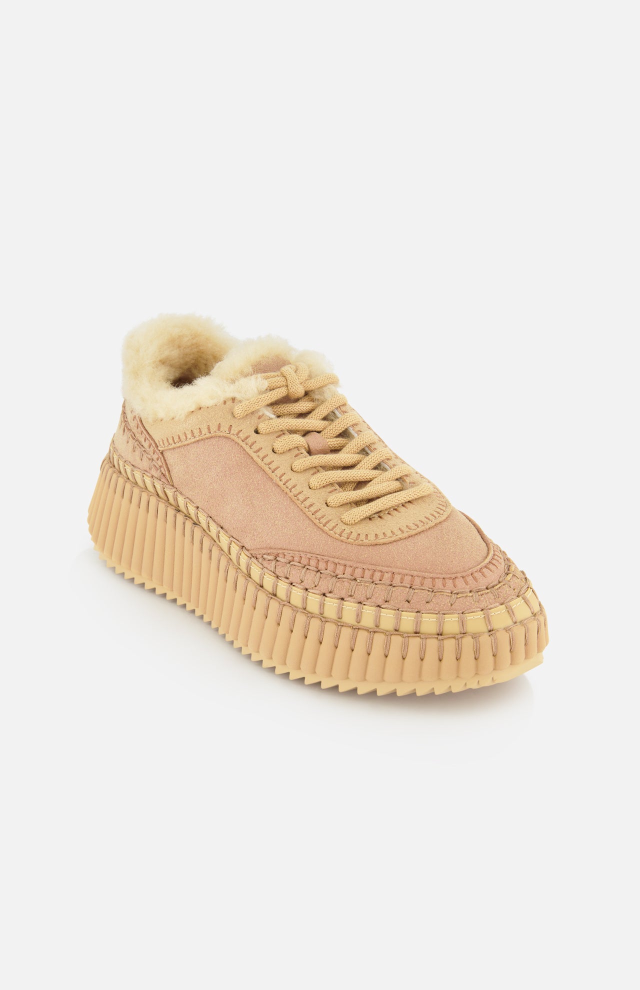 The CHLOÉ Nama Shearling Lining Sneakers feature a beige design with a thick, textured recycled sole, visible stitching, and a plush shearling lining on the inside, displayed on a white background.