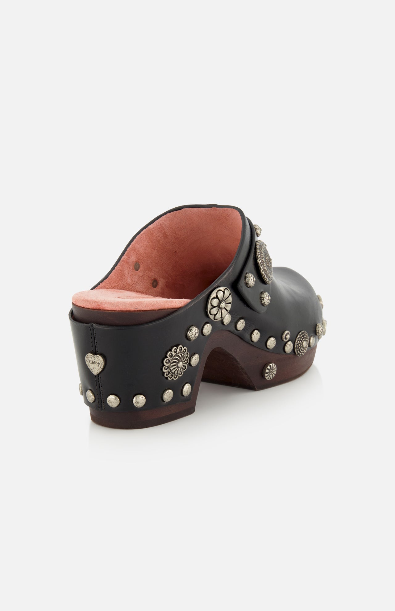 CHLOÉ Talis Studded Leather Clogs in black leather with a wooden platform heel, accented with decorative silver-tone studs in various floral and circular shapes, including a heart-shaped stud on the heel.